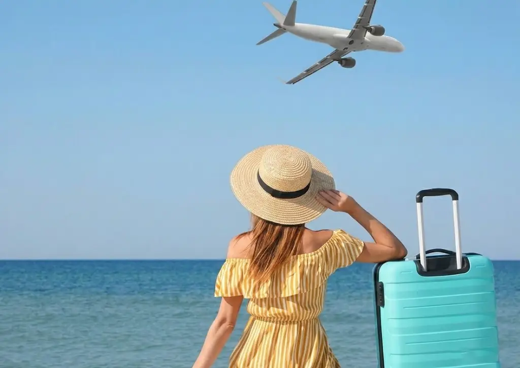 Traveler beginning a luxury Maldives vacation with a suitcase on a white-sand beach and an airplane overhead.