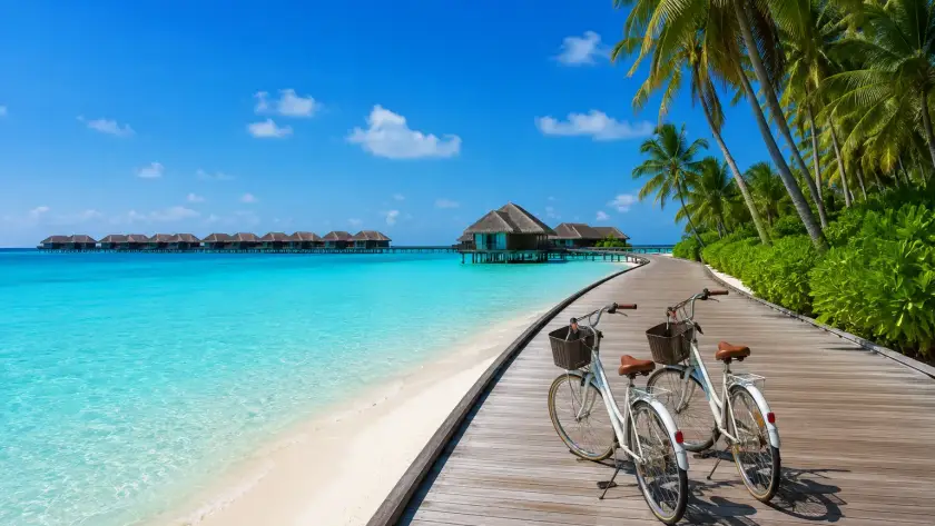 Bicycles parked on a wooden boardwalk overlooking turquoise waters and overwater villas in the Maldives 