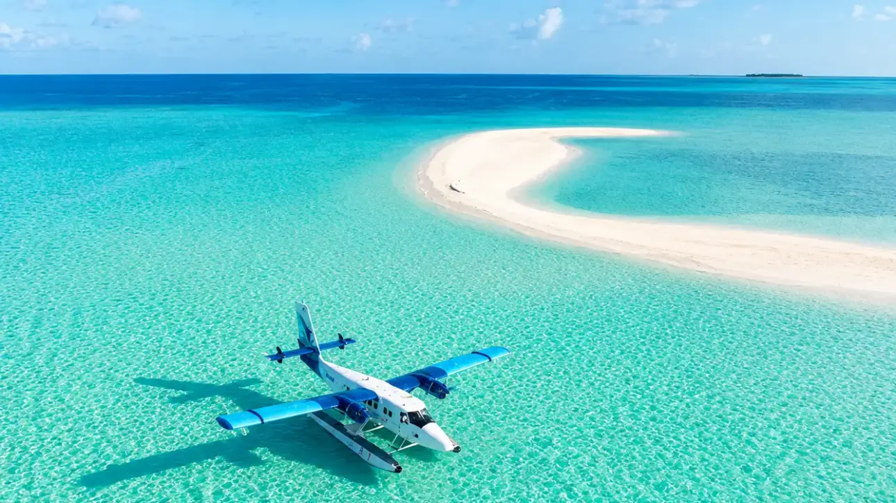 Seaplane floating on crystal-clear waters near a white sandbank in the Maldives