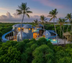 Luxury Maldives family resort villa with private pool, waterslides, and lush island scenery.