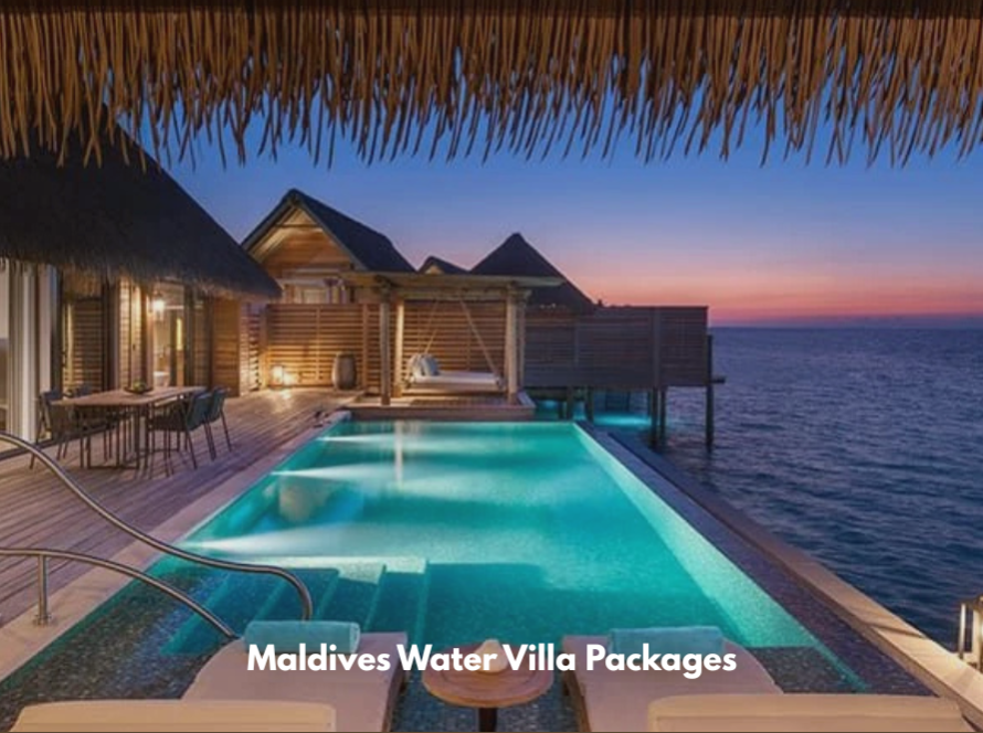Luxury overwater villa at dusk featuring a private illuminated infinity pool, wooden deck, lounge chairs, and panoramic ocean views.