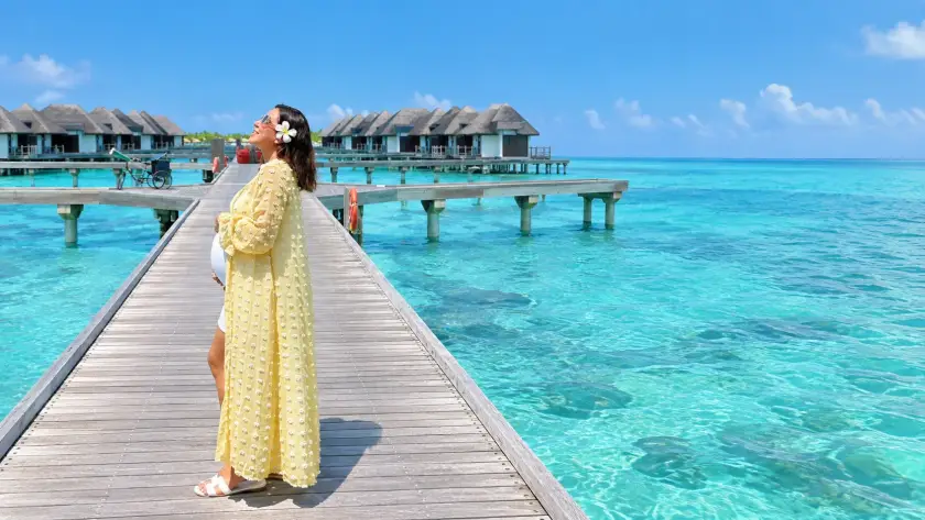 Pregnant woman relaxing on a white sandy Maldives beach beside crystal-clear turquoise water